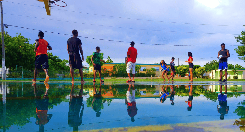 Kinder bei NPH spielen Basketball auf einem nassen Court.