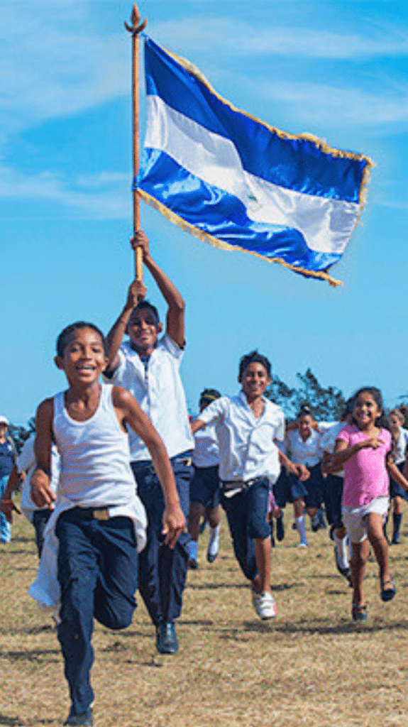 NPH-Kinderpatenschaft in Nicaragua: Eine Gruppe von Buben laufen und einer hält stolz die Flagge Nicaraguas in der Hand.