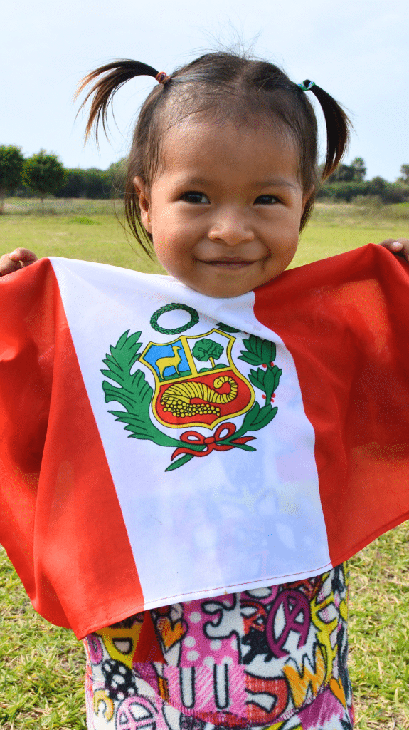 NPH Kinderpatenschaft für Peru, Mädchen hält eine peruanische Flagge in der Hand.