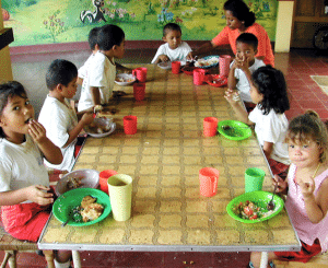 Mehrere Kinder am Tisch beim Essen; ausgewogene Mahlzeit sichtbar.
